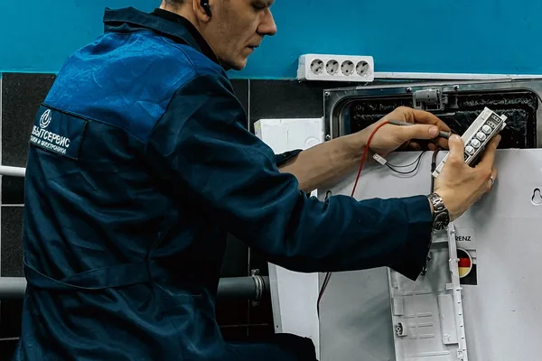 Técnico em uniforme azul fazendo manutenção em eletrodoméstico