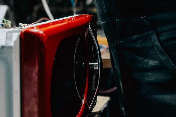 Técnico testando micro-ondas vermelho com ferramenta